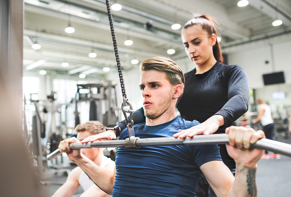 young man in the gym working out on a pull down machine